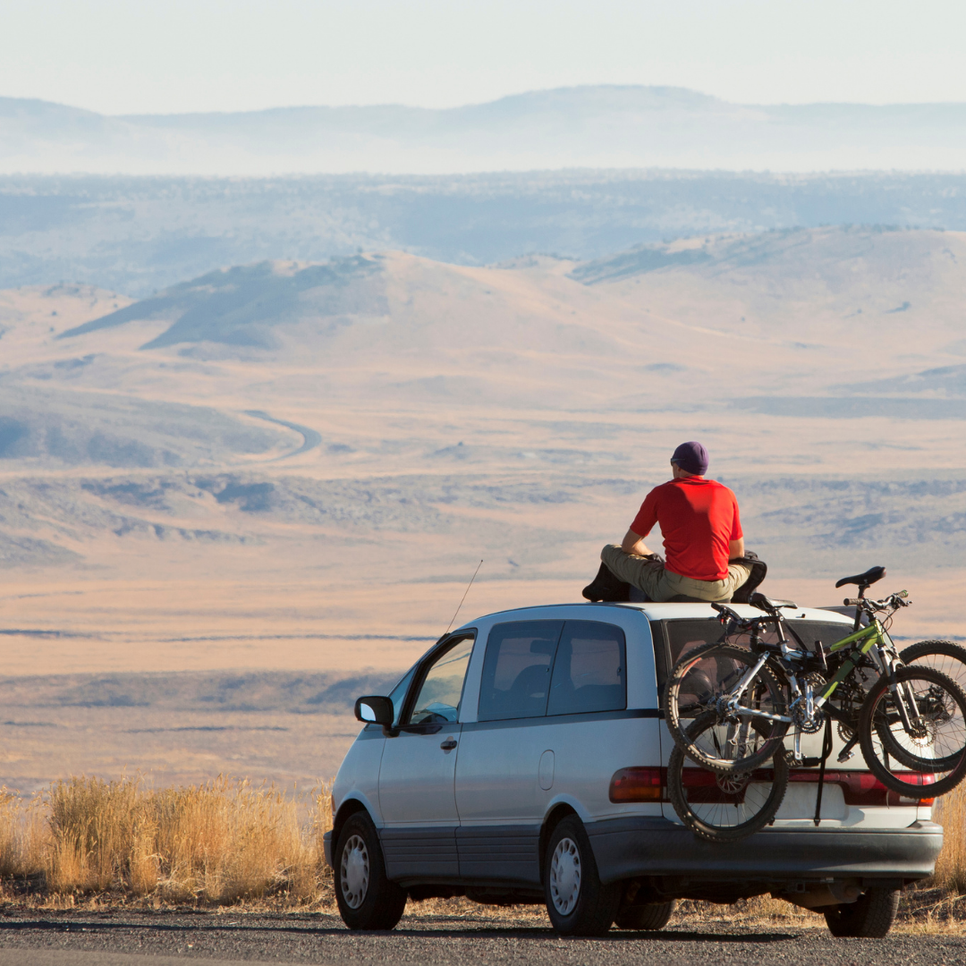 Image of a man on top of a car with a bike rack